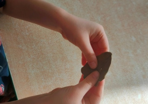 Dziecko palcami formuje placuszki plastelinowe.