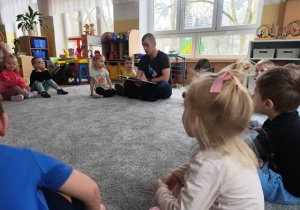 Tata koleżanki czyta dzieciom bajkę o Zuchozaurze.