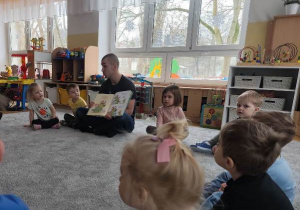 Gość pokazuje dzieciom ilustracje w książce.