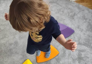 Dziecko przeskakuje z kamienia sensorycznego na kamień.