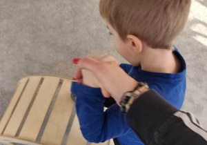 Dziecko z pomocą nauczyciela przechodzi po mostku.