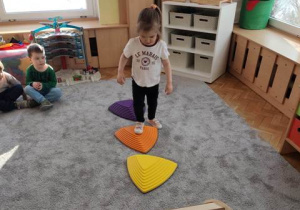 Dziewczynka przechodzi po kamieniach sensorycznych.