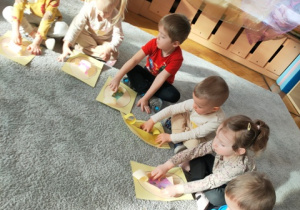 Dzieci rozdzierają papierowe jajka na swoich kartonach.