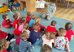 Chłopiec prezentuje dzieciom ilustrację odnoszącą się do przeczytanego tekstu.