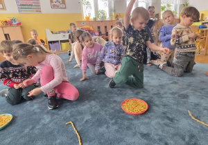 Rywalizacja międzyzespołowa - dzieci nawlekają na sznurek makaron penne.