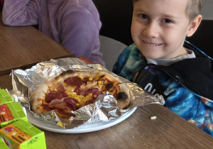Chłopiec cieszy się z upieczonej pizzy.
