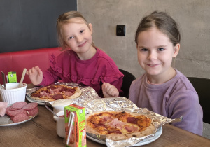 Dziewczynki prezentują swoje już upieczone pizze.