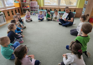 Tata Małgosi pokazuje ilustracje w książce.