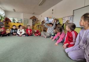 Dzieci siedzą na dywanie.