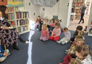 Dzieci siedzą i słuchają czytanego opowiadania.