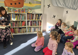 Dzieci siedzą w sali czytelniczej.