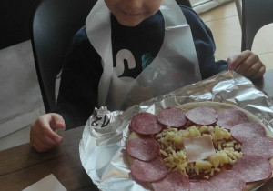 Chłopiec prezentuję pizzę.