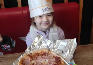 Dziewczynka prezentuję pizzę.