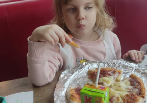 Dziewczynka je pizzę.