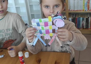 Dziewczynka prezentuje swoją pracę plastyczną.