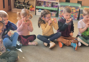 Dzieci siedzą na dywanie i ćwiczą oddech.