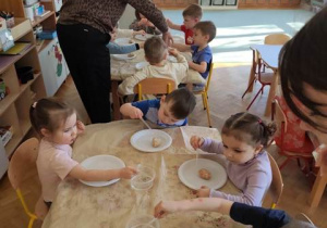 Dzieci zakraplają wodą z octem sodową kulę, aby znaleźć w jej wnętrzu skarb- ukrytego małego dinozaura.