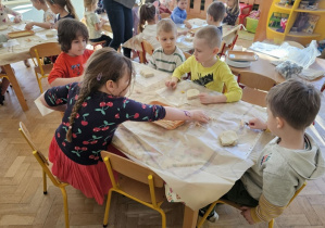 Dzieci wycinają w masie plastycznej dinozaury, odciskają szkielety dinozaurów.