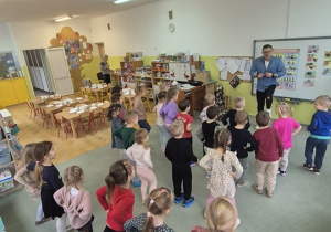 Dzieci stoją na dywanie i naśladują Pana Kamila.