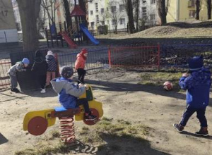 Dzieci bawią się w ogródku przedszkolnym wykorzystując zgromadzony w nim sprzęt.