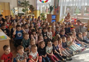 Dzieci siedzą na widowni i oglądają przedstawienie.