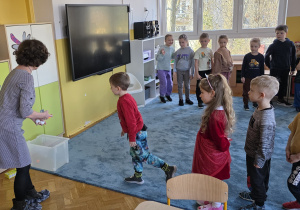 Dzieci muszą się skoncentrować i rzucić piłeczką do celu, stojąc przy tym na jednej nodze.