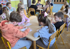 Dzieci wykonują zadanie przy stolikach. Muszą stworzyć coś z czterech kół.