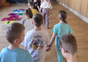 Dzieci ustawione parami zmierzają korytarzem szkolnym.