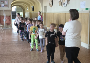 Dzieci spacerują kolejnym szkolnym korytarzem.