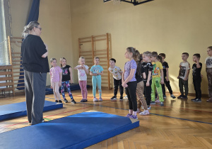 Dzieci podczas zajęć sportowych na sali gimnastycznej.