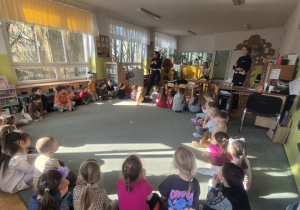 Dzieci siedzą na dywanie i słuchają.