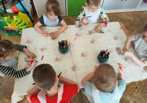 Dzieci kolorują mazakami sylwetę jajka wyciętą ze sklejki.