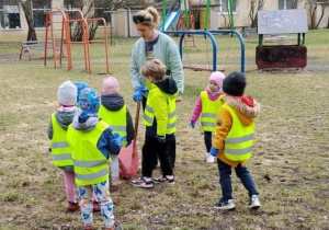 "Pszczółki" wraz z ciocią Asią wypełniają worek zebranymi śmieciami.