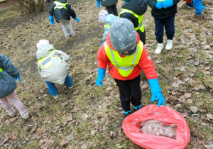 Dziecko wrzuca do foliowego worka zebrane śmieci.