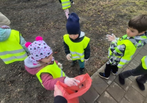 Dzieci sprzątają pobliski trawnik.
