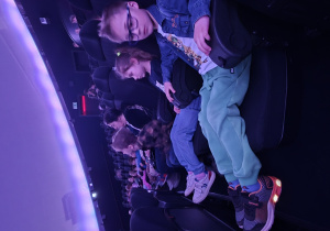 Dzieci siedzą i czekają na rozpoczęcie seansu "Kosmos dla najmłodszych".