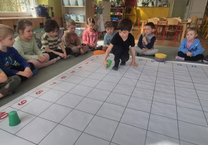 Chłopiec zaczyna układać pierwsze elementy z zakodowanego obrazka.