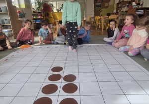 Dziewczynka rozmieszcza na macie do kodowania kolejne elementy.