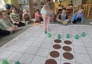 Dziewczynka rozmieszcza na macie do kodowania kolejne elementy.