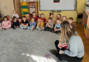 Dzieci siedzą na dywanie. Słuchają wypowiedzi gościa.