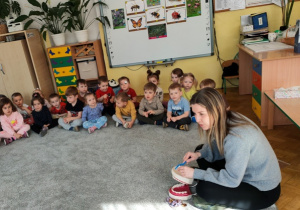 Pani stomatolog pokazuje dzieciom jak prawidłowo myć zęby, wykorzystując model szczęki stomatologicznej.