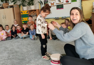 Dziecko otrzymuje medal za poprawne odpowiedzi na pytania prowadzącej.