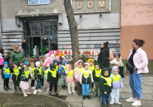 Dzieci stoją ustawione w pary przed teatrem. Czekają na transport.