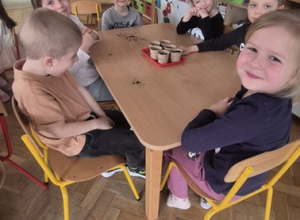 Dzieci siedzą przy stolikach ze swoim zasadzonym owsem.