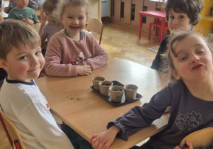 Dzieci siedzą i czekają, żeby podlać swoje swoje sadzonki.