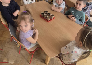 Dzieci siedzą i czekają na podlanie swoich sadzonek.