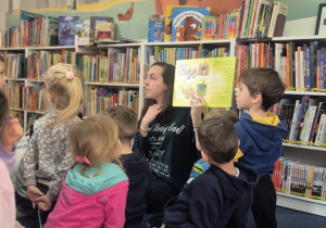 Pani z biblioteki pokazuje ilustracje w książki.
