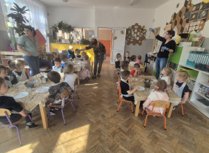 Wszystkie dzieci siedzą przy stolikach.