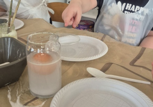 Dziewczynka obserwuje jak zachowuje się jajko włożone do solanki.