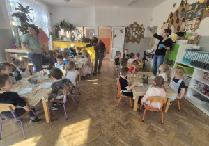 Dzieci siedzą przy stolikach i obserwują co stanie się z jajkiem włożonym do solanki.